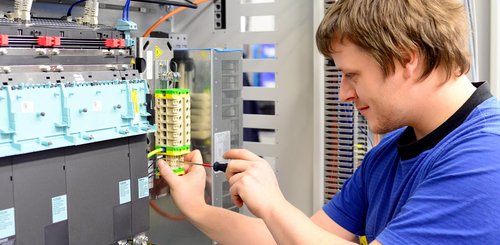 Ein Elektroniker der an einer Klemmverbindung schraubt